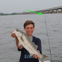 A Litlle happy boy showing a white fish on a evening in a bridge background