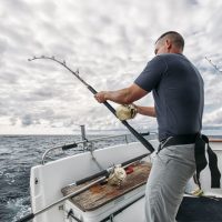 A man trolling his fishing rod from a motor boat