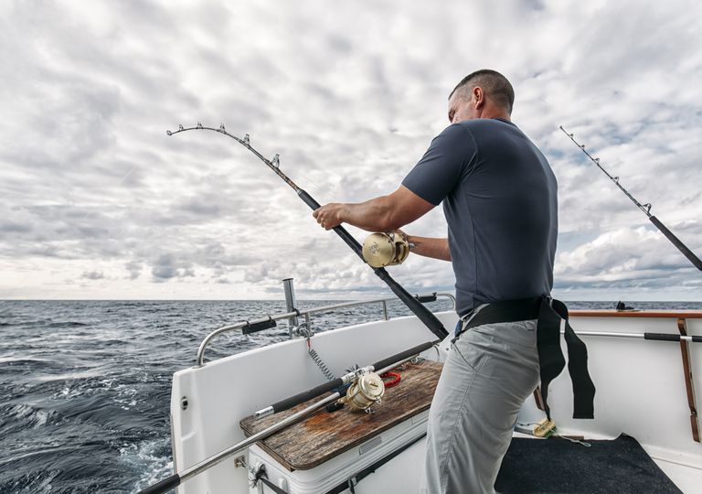 A man trolling his fishing rod from a motor boat