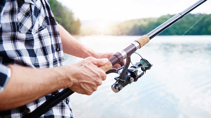 On A Sunny Day, A Man Holding The Fishing Rod For Fishing.