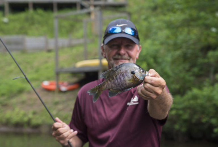 An Old Man Catched A Bream Fish And Show It To The Camera.