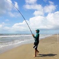 Man Casting A Fishing Line Into surf