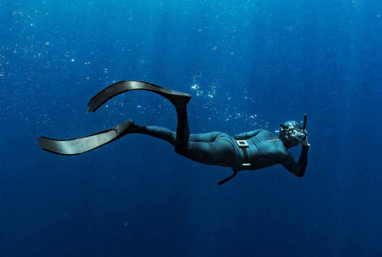 A Spearfisher Swims In The Blue Sea.